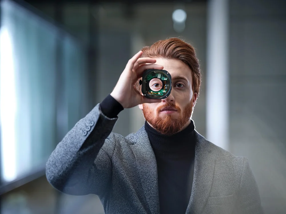 [Translate to Chinese:]  A closeup of a redhead man looking through a camera lens