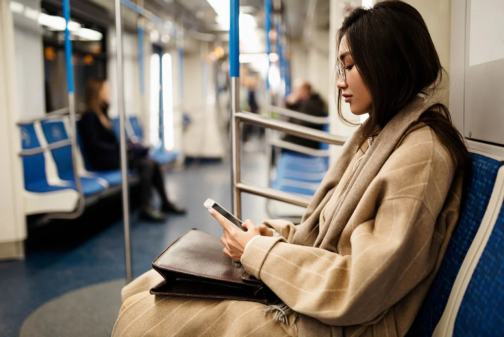 [Translate to Chinese:] a young woman looks at her mobile phone while sitting in the train